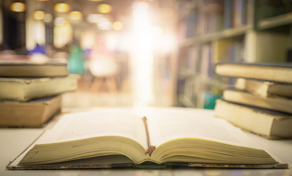 Opening holy bible with blurred cross background